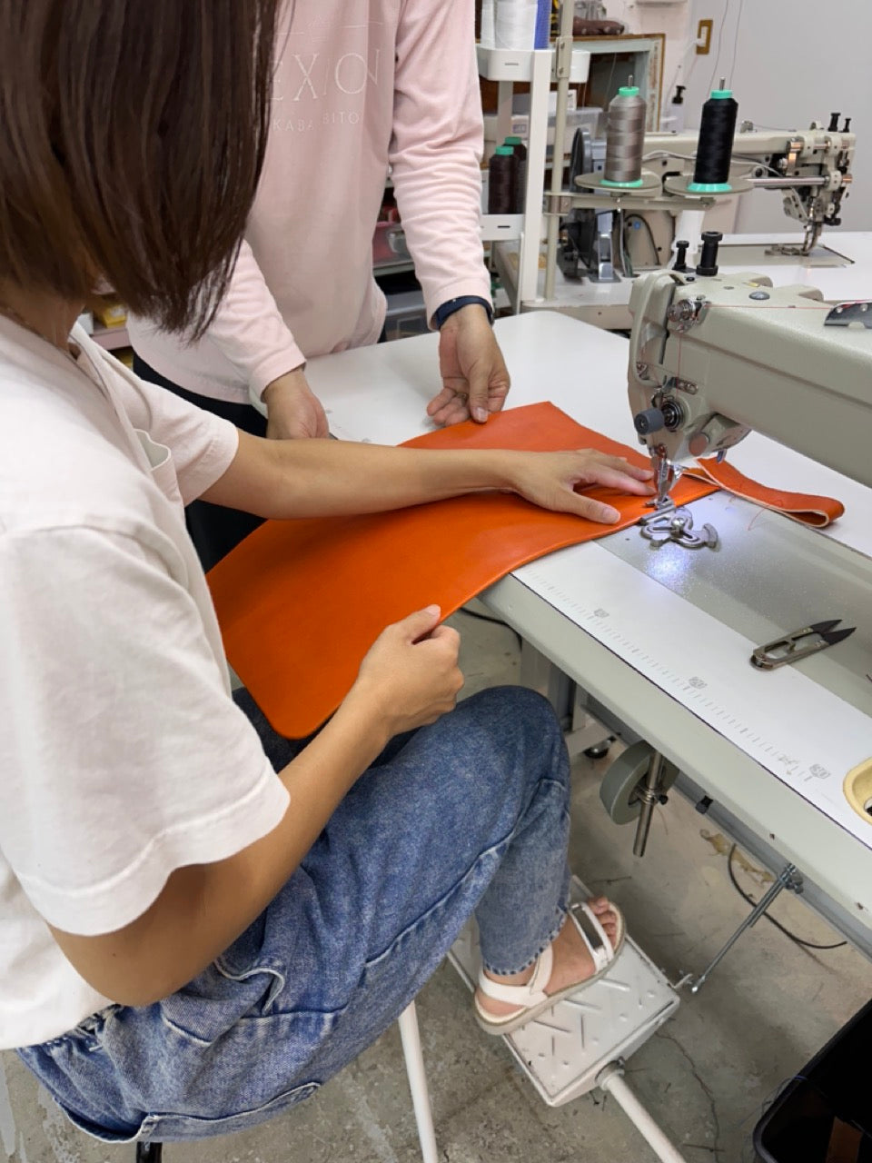 お母さんがミシンでランドセルのパーツを縫っているシーン